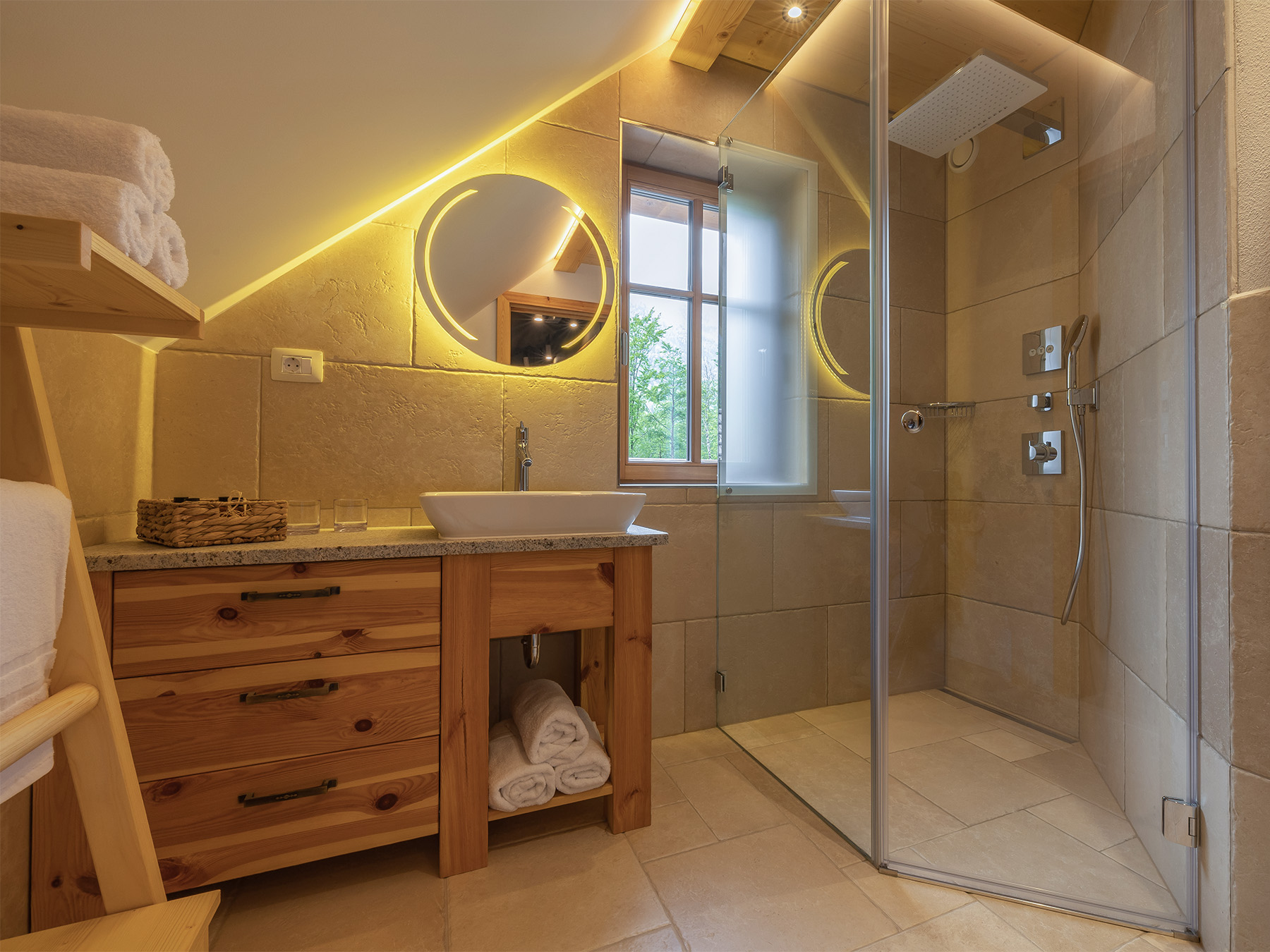 Kopalnica z walk-in masažno prho in osvetljenim ogledalom v Alpskem SPA Chaletu ob Bohinjskem jezeru.