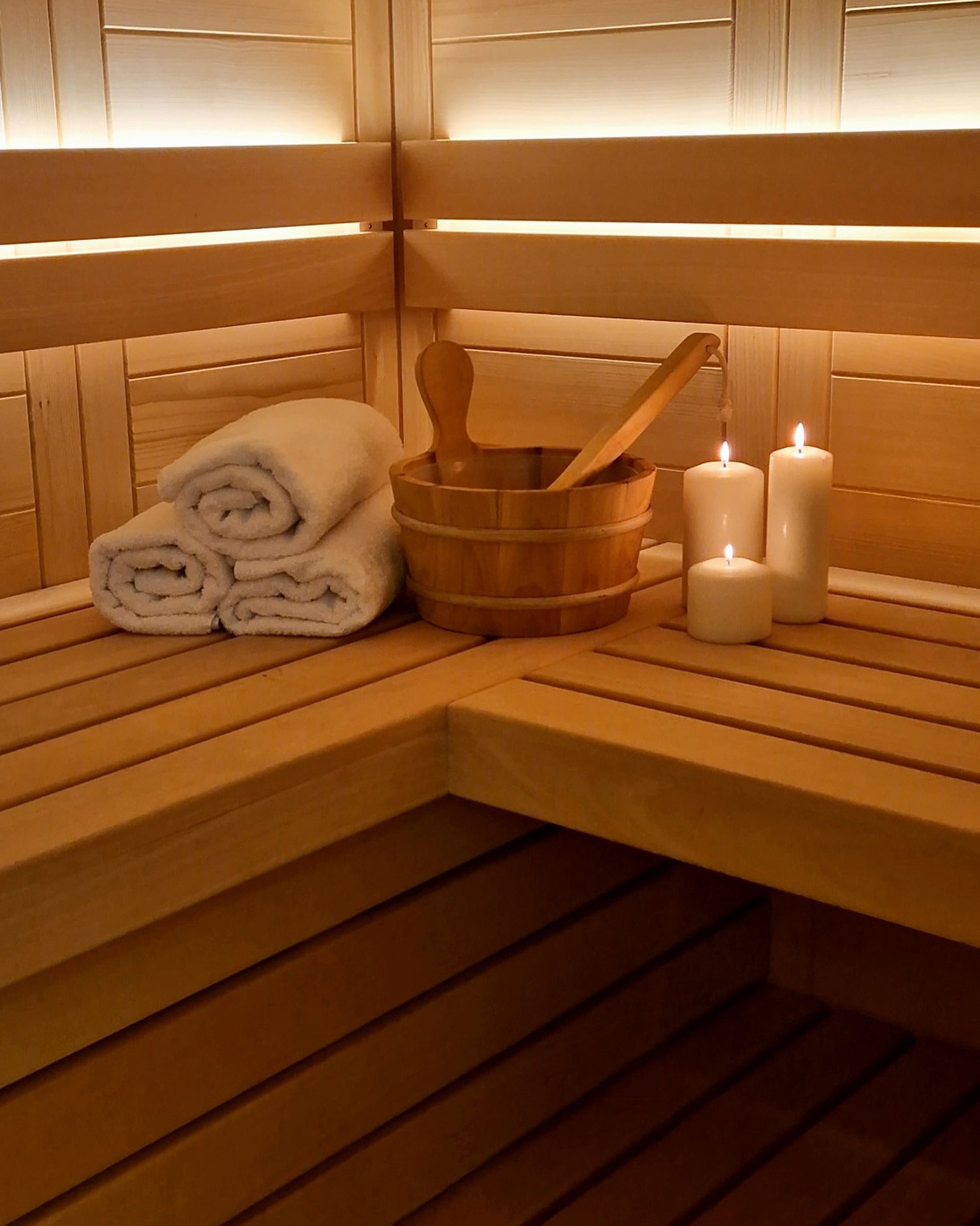 Detajl finske saune z brisačami, vedrom in svečami v zasebnem SPA Chalet ob Bohinjskem jezeru.